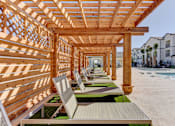Thumbnail 58 of 80 - A wooden pergola with lounge chairs is situated on a sandy beach.