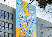 Thumbnail 3 of 15 - A large mural of a colorful abstract design on a building.