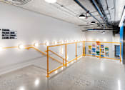 Thumbnail 12 of 15 - A long hallway with orange railings and lights on them.