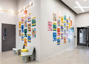 Thumbnail 10 of 15 - A hallway with a wall of posters and two chairs.