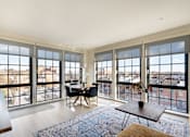 Thumbnail 6 of 15 - A living room with a view of the city through large windows.