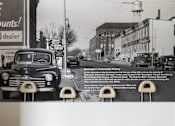 Thumbnail 15 of 15 - A black and white photo of an old car is displayed on a wall.