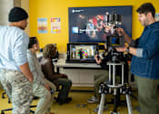 Thumbnail 8 of 15 - A man in a blue shirt is operating a camera in front of a screen displaying the title "Once Upon A Night".