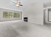 Thumbnail 27 of 40 - A spacious room with a ceiling fan and a fireplace.