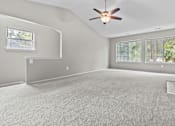 Thumbnail 37 of 40 - A spacious room with a ceiling fan and carpeted floor.