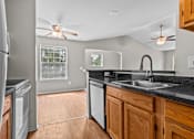Thumbnail 31 of 40 - A modern kitchen with a black countertop and wooden cabinets.