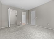 Thumbnail 19 of 40 - A large, empty room with a carpeted floor and two doors.