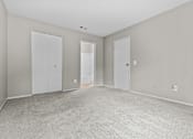 Thumbnail 36 of 40 - A room with grey carpet and white doors.