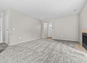 Thumbnail 39 of 40 - A large, empty room with a fireplace and carpeted floor.