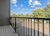 Thumbnail 39 of 39 - A balcony with a black railing overlooks a parking lot.