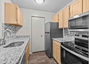 Thumbnail 38 of 40 - A kitchen with black appliances and wooden cabinets.