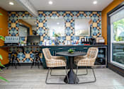 Thumbnail 37 of 57 - A kitchen with a table and chairs in front of a tiled wall.