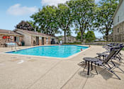 Thumbnail 14 of 29 - A swimming pool surrounded by chairs and trees.