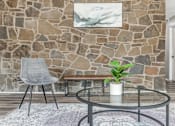 Thumbnail 8 of 50 - A grey chair sits in front of a stone wall with a plant on the table.