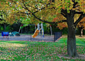 Thumbnail 15 of 18 - a swing set in a park next to a tree