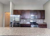 Thumbnail 18 of 22 - Kitchen with dark cherry cabinets, granite counter tops, and stainless steal appliances.