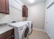 Thumbnail 16 of 22 - Laundry room with tile floors, washer and dryer, cabinets, and hanging rack.