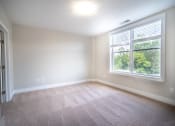 Thumbnail 14 of 22 - Bedroom with plush carpeting, cream walls, and a large picture window.