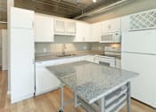 Thumbnail 6 of 47 - a kitchen with a granite counter top and white appliances at Ann Arbor City Club, Ann Arbor Michigan
