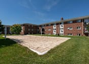 Thumbnail 12 of 20 - an empty volleyball court in front of a brick building at Village Club of Royal Oak, Royal Oak