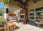 Thumbnail 10 of 20 - a covered patio with a fireplace and chairs at Village Club of Royal Oak, Royal Oak, MI