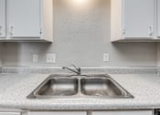 Thumbnail 36 of 50 - A kitchen with a double sink and white cabinets.