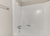 Thumbnail 28 of 50 - A white bathtub with a shower head and faucet.