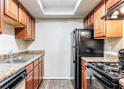 Thumbnail 7 of 50 - A kitchen with black appliances and wooden cabinets.