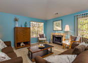 Thumbnail 9 of 26 - A living room with a fireplace and a brown couch.
