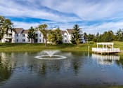 Thumbnail 17 of 26 - a fountain in the middle of a pond with apartments in the background at Village Club of Farmington Hills, Farmington Hills, MI 48331