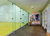 Thumbnail 25 of 26 - A hallway with glass walls and yellow flooring.