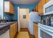 Thumbnail 11 of 26 - A kitchen with white appliances and wooden cabinets.