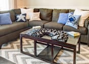 Thumbnail 35 of 37 - A living room with a grey couch and a coffee table.