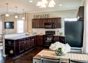 Thumbnail 36 of 37 - A kitchen with dark brown cabinets and a black refrigerator.