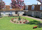 Thumbnail 8 of 47 - A tree with pink flowers is in the middle of a grassy area in front of a building.
