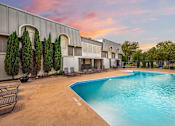 Thumbnail 9 of 47 - A swimming pool is surrounded by a building and trees.