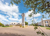 Thumbnail 6 of 47 - A clock tower stands in the middle of a parking lot.