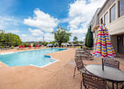 Thumbnail 10 of 47 - A pool area with chairs and a table with an umbrella.