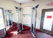 Thumbnail 21 of 47 - A gym with a red carpet and a row of exercise machines.