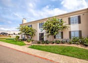 Thumbnail 19 of 47 - A beige building with a green lawn in front.