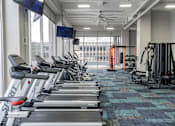 Thumbnail 15 of 47 - a gym with cardio equipment and a large window