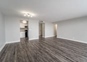 Thumbnail 35 of 47 - an empty living room with wood flooring and a kitchen