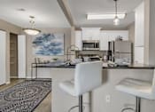 Thumbnail 13 of 17 - an open kitchen and living room with a bar and white chairs
