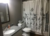 Thumbnail 13 of 14 - Bathroom with grey counter and white sink and toilet.  Floral patterned shower curtain.