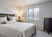 Thumbnail 5 of 10 - A bedroom with a large bed and a nightstand with a lamp.