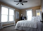 Thumbnail 26 of 66 - Primary bedroom with plush bed, carpeting, large windows, and a ceiling fan.