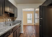 Thumbnail 2 of 18 - A kitchen with black cabinets and a black refrigerator.