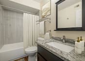 Thumbnail 3 of 18 - A bathroom with a white tub, sink, and toilet.