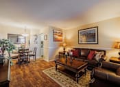 Thumbnail 7 of 18 - A living room with a brown leather couch and a wooden coffee table.