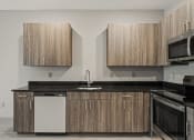 Thumbnail 3 of 18 - a kitchen with wooden cabinets and a black counter top